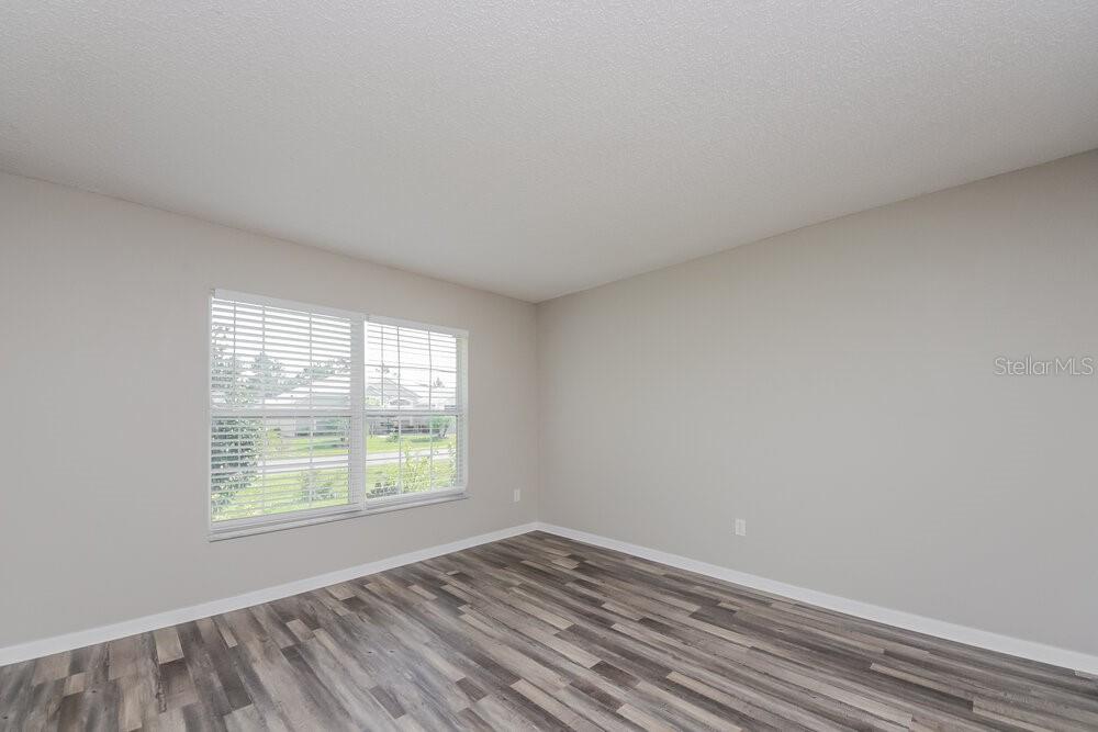 An empty bedroom features light gray walls, white trim, and wood-look laminate flooring — 46 DORSET DRIVE, KISSIMMEE, FL