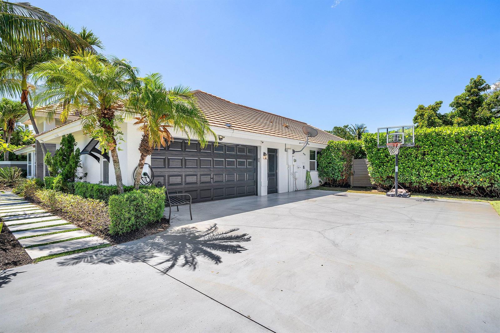 A white house exterior features a dark garage door, a driveway, and a basketball hoop — 916 SW 37th Court, Boynton Beach FL 33435, BOYNTON BEACH, FL