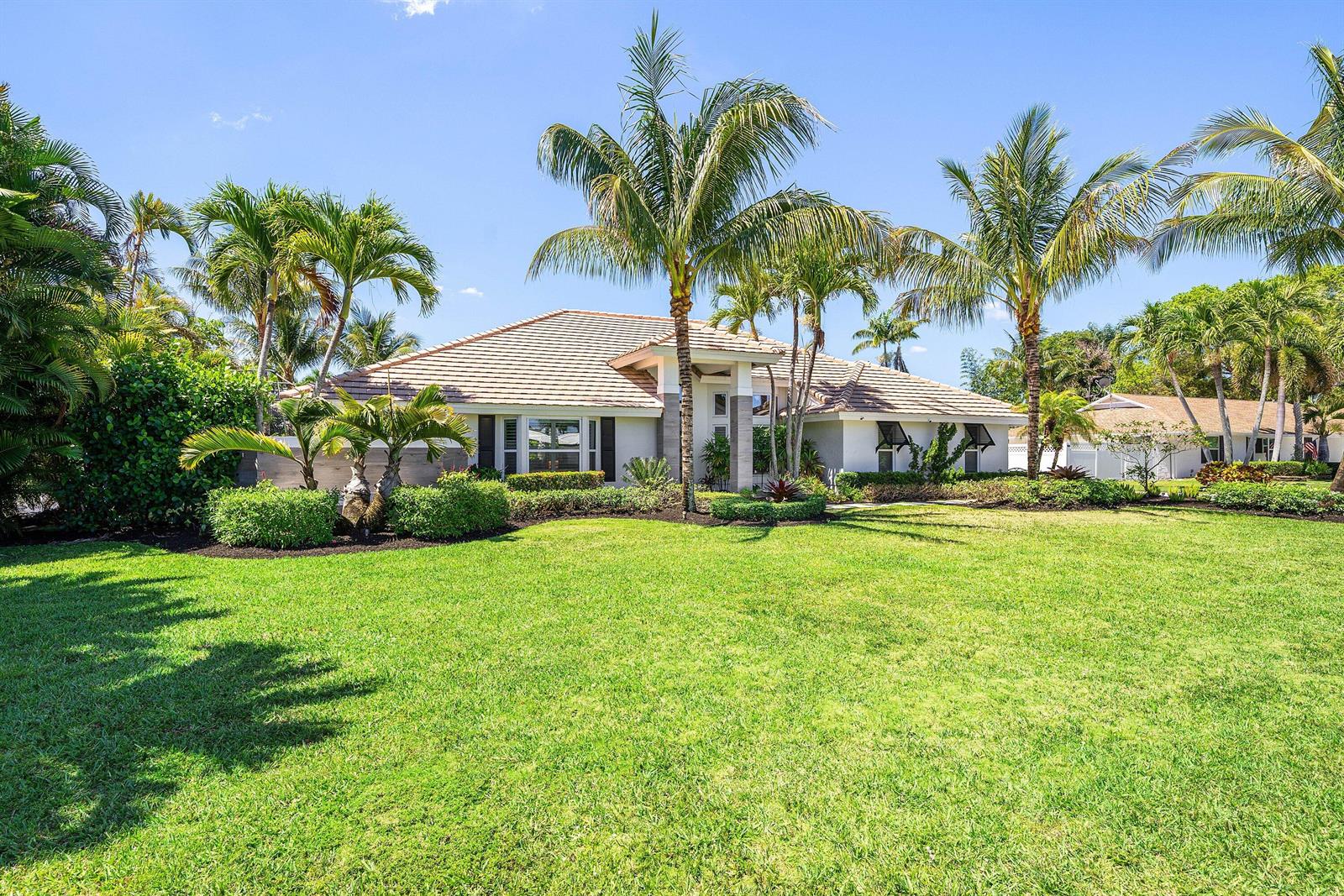 A single-story house with a tiled roof and palm trees sits behind a large lawn — 916 SW 37th Court, Boynton Beach FL 33435, BOYNTON BEACH, FL