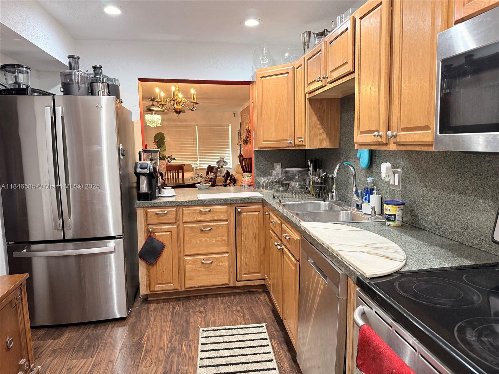 A kitchen features wood cabinets, stainless steel appliances, and a gray countertop — 215 SE 3rd Ave # 102C, Hallandale Beach FL 33009, HALLANDALE BEACH, FL