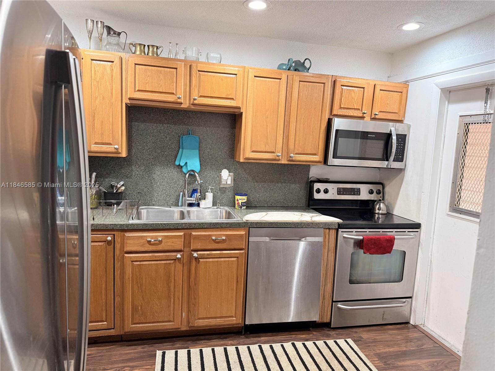 A kitchen features oak cabinets, stainless steel appliances, and a dark speckled countertop — 215 SE 3rd Ave # 102C, Hallandale Beach FL 33009, HALLANDALE BEACH, FL