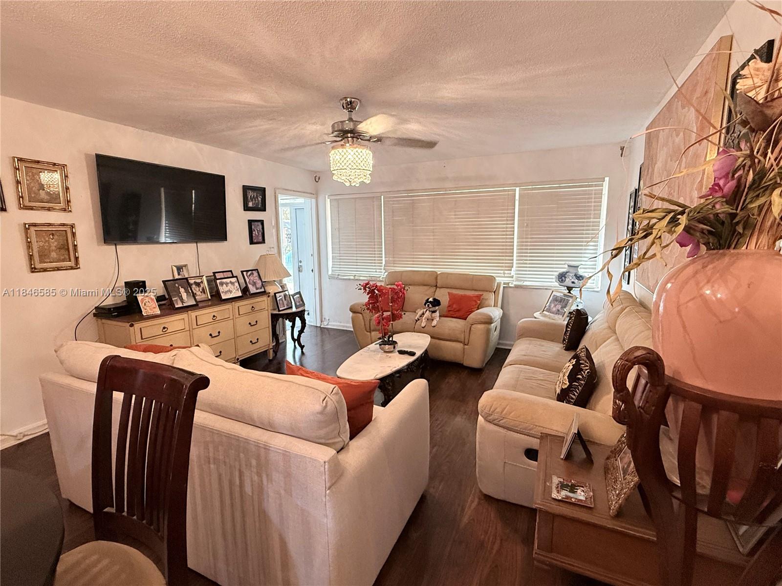 A living room features light-colored sofas, a ceiling fan, a television, and dark wood flooring — 215 SE 3rd Ave # 102C, Hallandale Beach FL 33009, HALLANDALE BEACH, FL