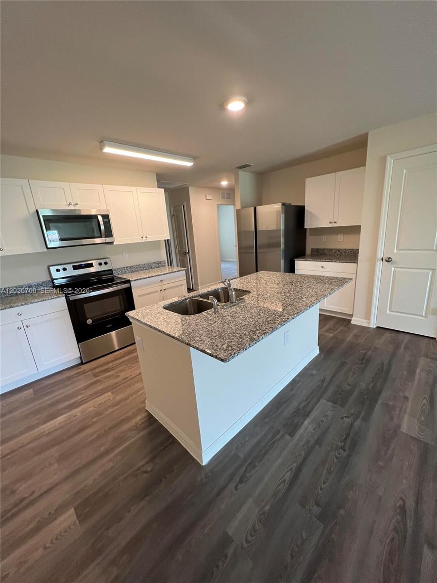 A kitchen features white cabinets, granite countertops, stainless steel appliances, and a central island — 9114 Aegean Cir, Lehigh Acres FL 33936, LEHIGH ACRES, FL