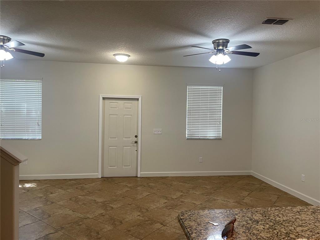 A room with tile flooring, two ceiling fans, a door, and two windows with blinds — 7283 PENKRIDGE LANE, WINDERMERE, FL