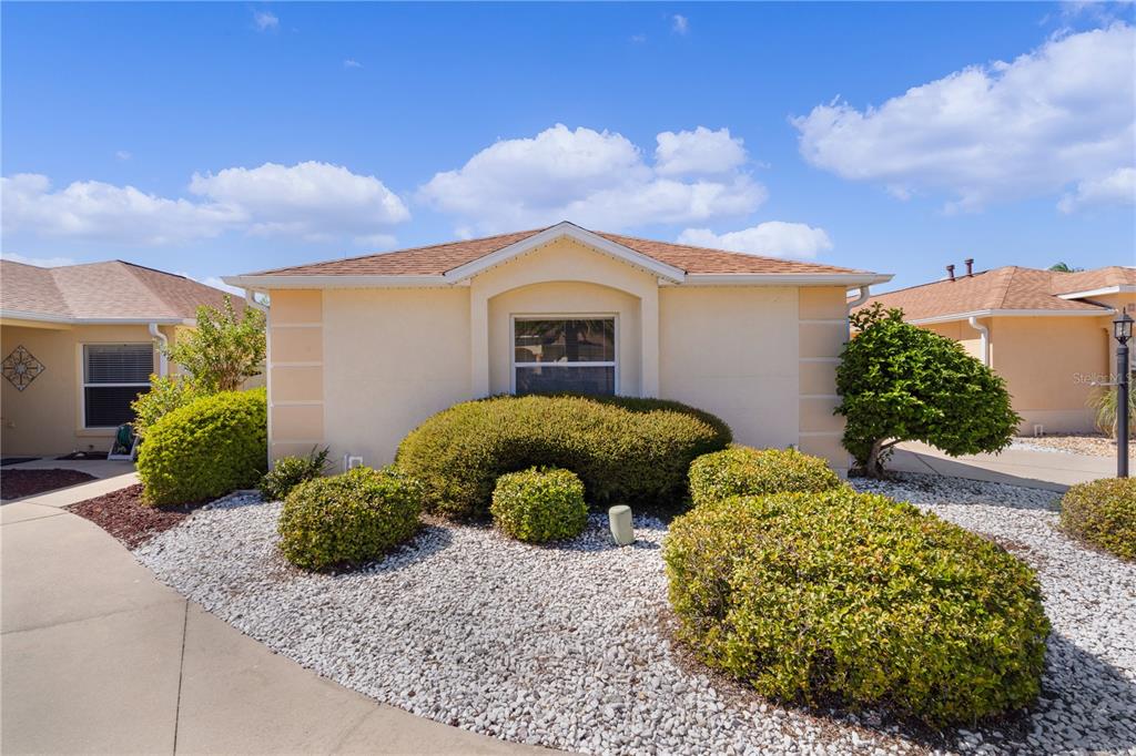 A single-story house with a beige stucco exterior, a shingled roof, and a landscaped front yard — 1116 SAN BERNARDO ROAD, THE VILLAGES, FL