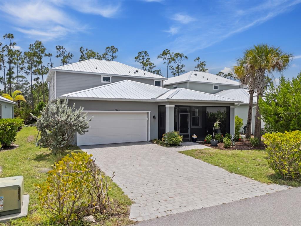 A two-story gray house with a metal roof, a paved driveway, and a screened entryway — 42211 HAMMOCK LANE, PUNTA GORDA, FL