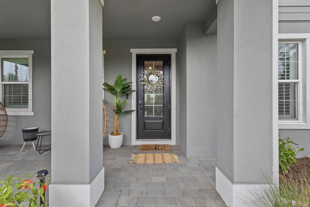 A gray exterior entryway features a black front door with a wreath and a doormat — 42211 HAMMOCK LANE, PUNTA GORDA, FL