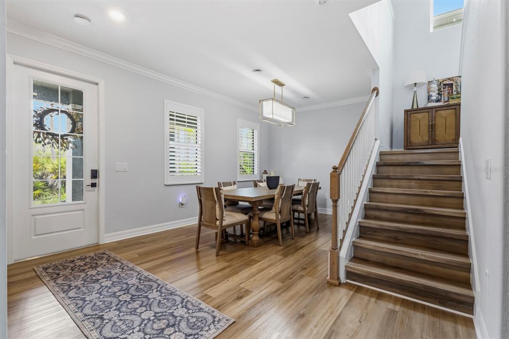 An entryway with wood flooring, a dining table, and a staircase leading to the upper level — 42211 HAMMOCK LANE, PUNTA GORDA, FL