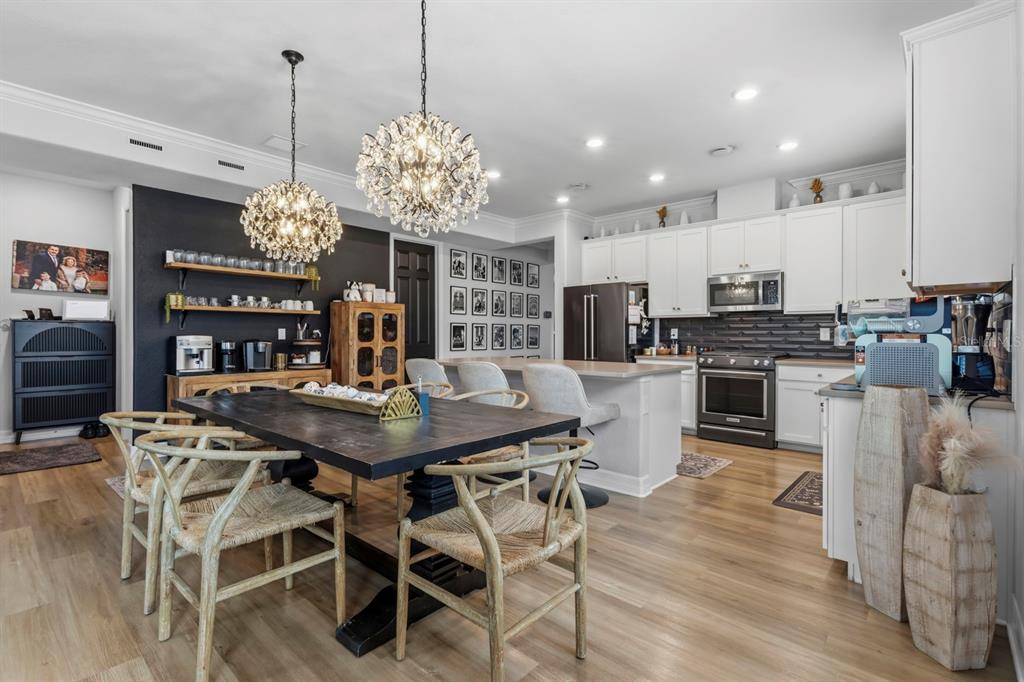 A dining area and kitchen feature a dark wood table, crystal chandeliers, and white cabinetry — 42211 HAMMOCK LANE, PUNTA GORDA, FL