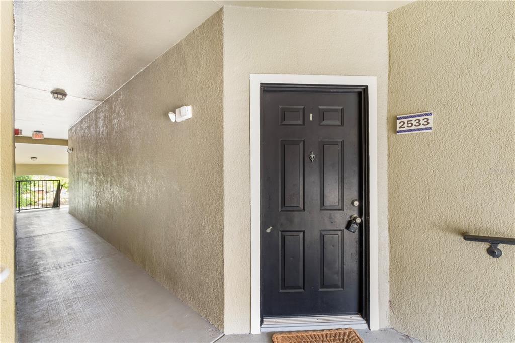 A black front door with a lockbox is located at the end of a walkway — 6025 WESTGATE DRIVE UNIT 2533, ORLANDO, FL