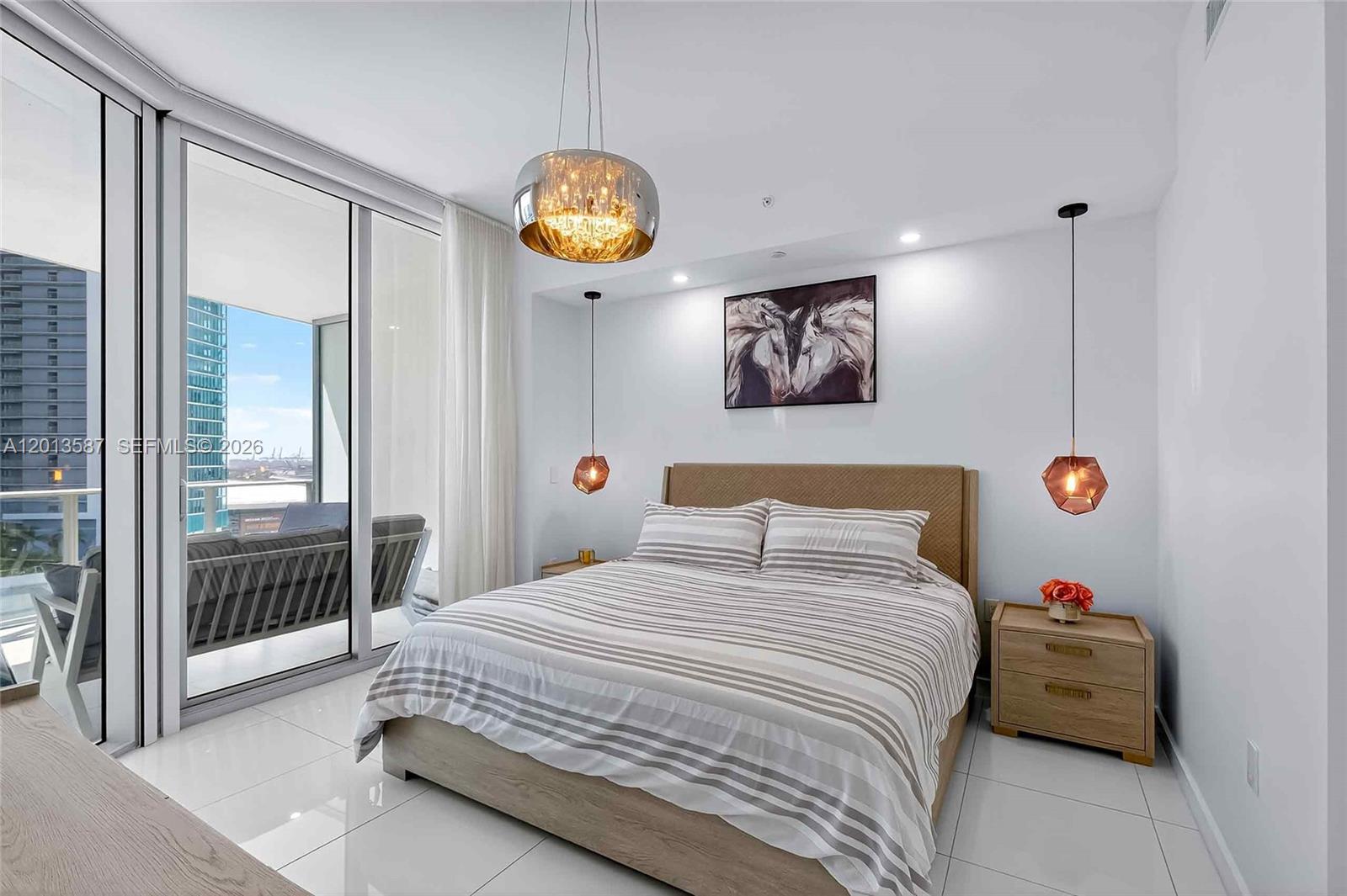 A modern bedroom features a bed, two pendant lights, and a balcony with city views — 851 NE 1st Ave # 1603, Miami FL 33132, MIAMI, FL