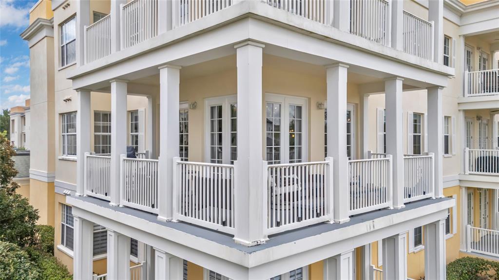 A multi-story building features white railed balconies with columns and French doors — 7474 EXCITEMENT DR UNIT 203, REUNION, FL