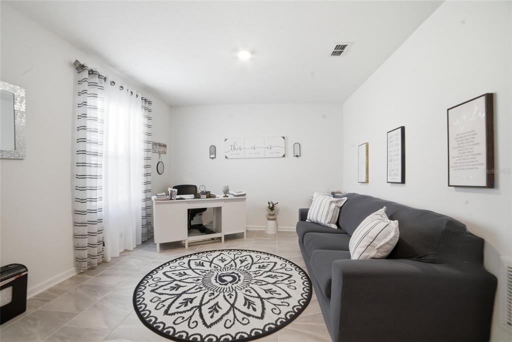 A home office features a desk, a gray sofa, and a circular patterned area rug — 4980 FOUR STRAND COURT, ST CLOUD, FL