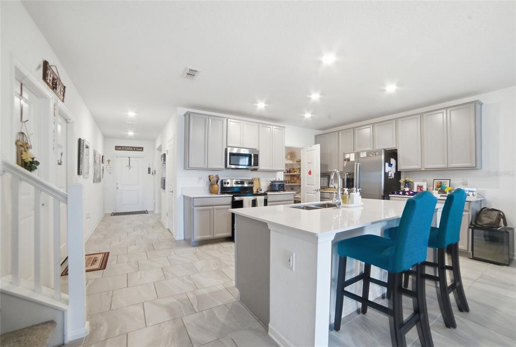 A kitchen with light gray cabinets, a white island, and blue bar stools — 4980 FOUR STRAND COURT, ST CLOUD, FL