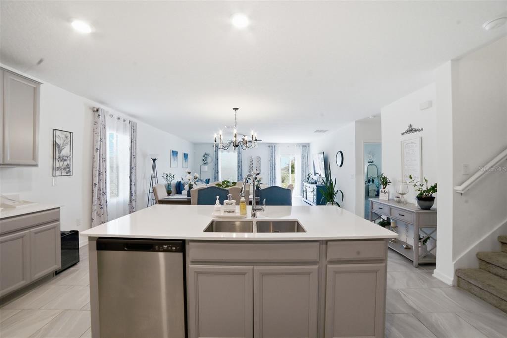 A kitchen island with a stainless steel dishwasher and sink overlooks an open dining area — 4980 FOUR STRAND COURT, ST CLOUD, FL