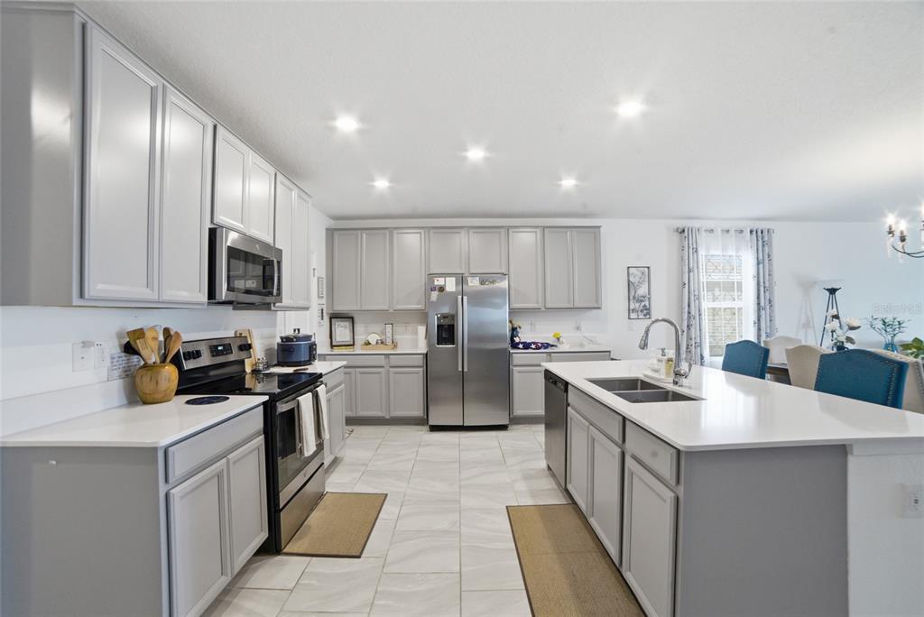 A kitchen with gray cabinets, stainless steel appliances, white countertops, and light tile flooring — 4980 FOUR STRAND COURT, ST CLOUD, FL