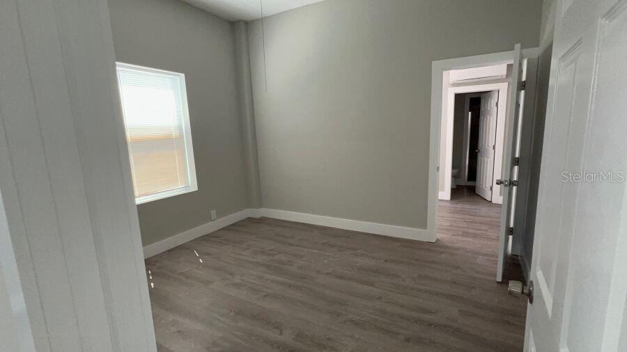 An empty bedroom with gray walls, wood-look flooring, and a doorway leading to another room — 706 HARVEY, DAYTONA BEACH, FL