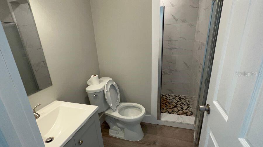 A small bathroom features a gray vanity, a white toilet, and a tiled walk-in shower — 706 HARVEY, DAYTONA BEACH, FL