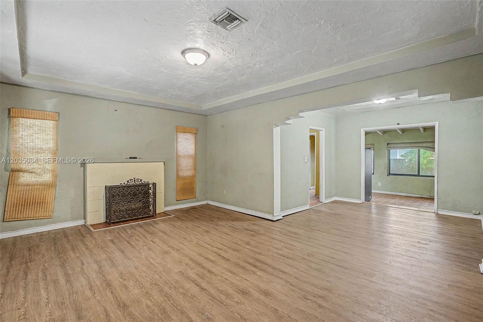 A living room features light green walls, wood-look flooring, and a fireplace with a screen — 583 NW 47th St, Miami FL 33127, MIAMI, FL