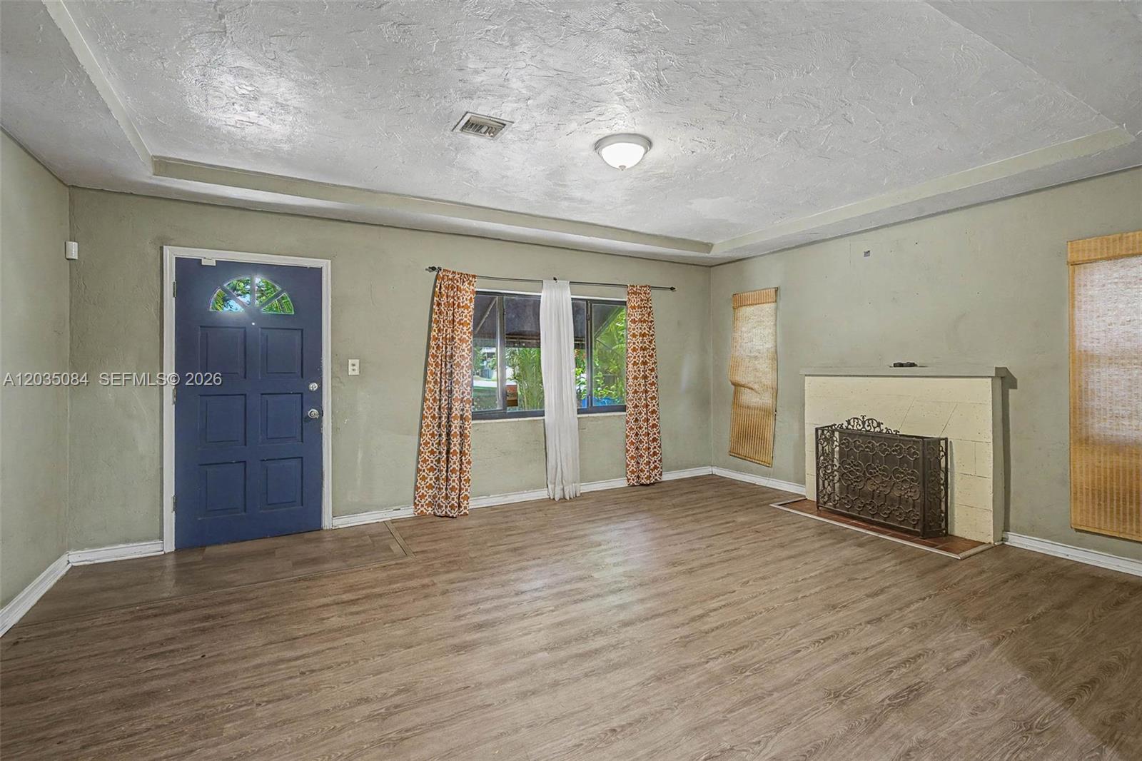 A living room features light green walls, wood-look flooring, a fireplace, and a blue door — 583 NW 47th St, Miami FL 33127, MIAMI, FL