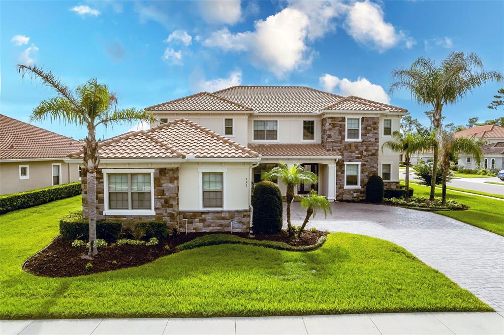 A two-story suburban house with a stone facade, tile roof, and a paved driveway — 427 BLUE BIRCH COURT, SANFORD, FL