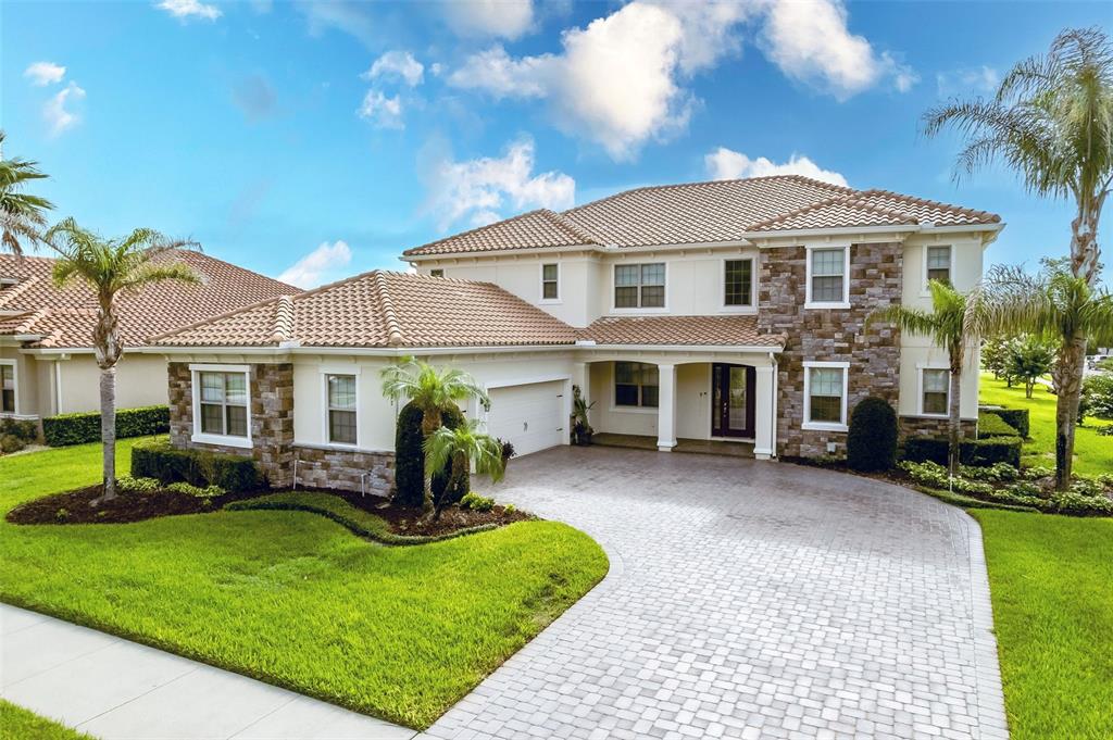 A two-story house with a tiled roof, stone facade, and a paved driveway — 427 BLUE BIRCH COURT, SANFORD, FL