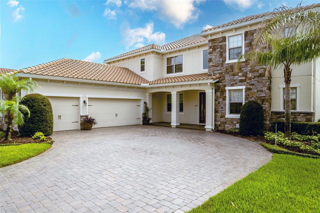 A two-story house with a stone facade, tile roof, and a paved circular driveway — 427 BLUE BIRCH COURT, SANFORD, FL