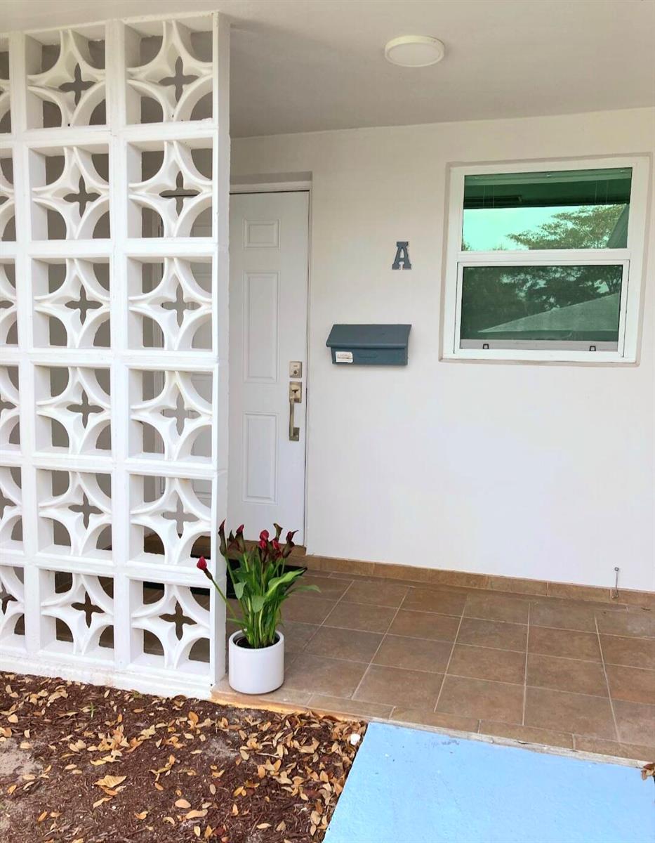 A white door with a mailbox, a decorative breeze block wall, and a potted plant — 1155 S Drive Circle # A, Delray Beach FL 33445, DELRAY BEACH, FL
