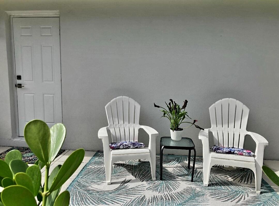 A patio area features two white Adirondack chairs, a small table, and a patterned rug — 1155 S Drive Circle # A, Delray Beach FL 33445, DELRAY BEACH, FL