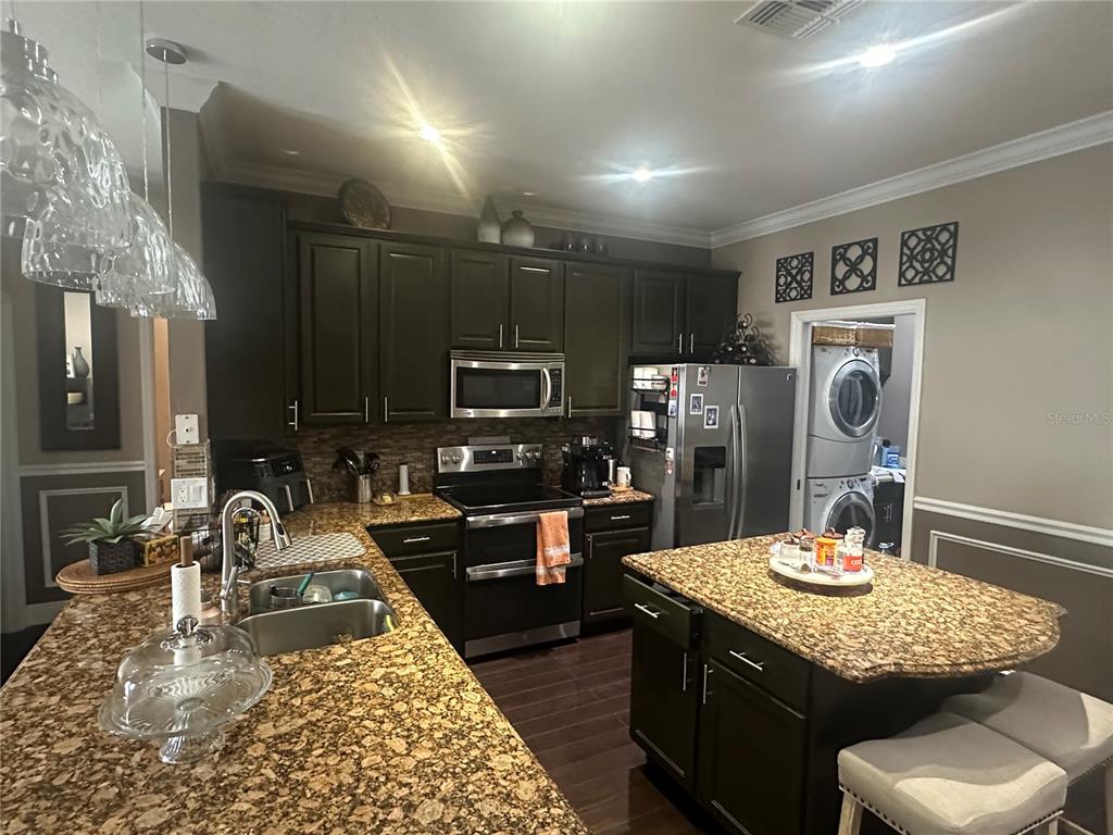 A kitchen features dark wood cabinets, granite countertops, a center island, and stainless steel appliances — 2131 RIBBON FALLS PARKWAY, ORLANDO, FL