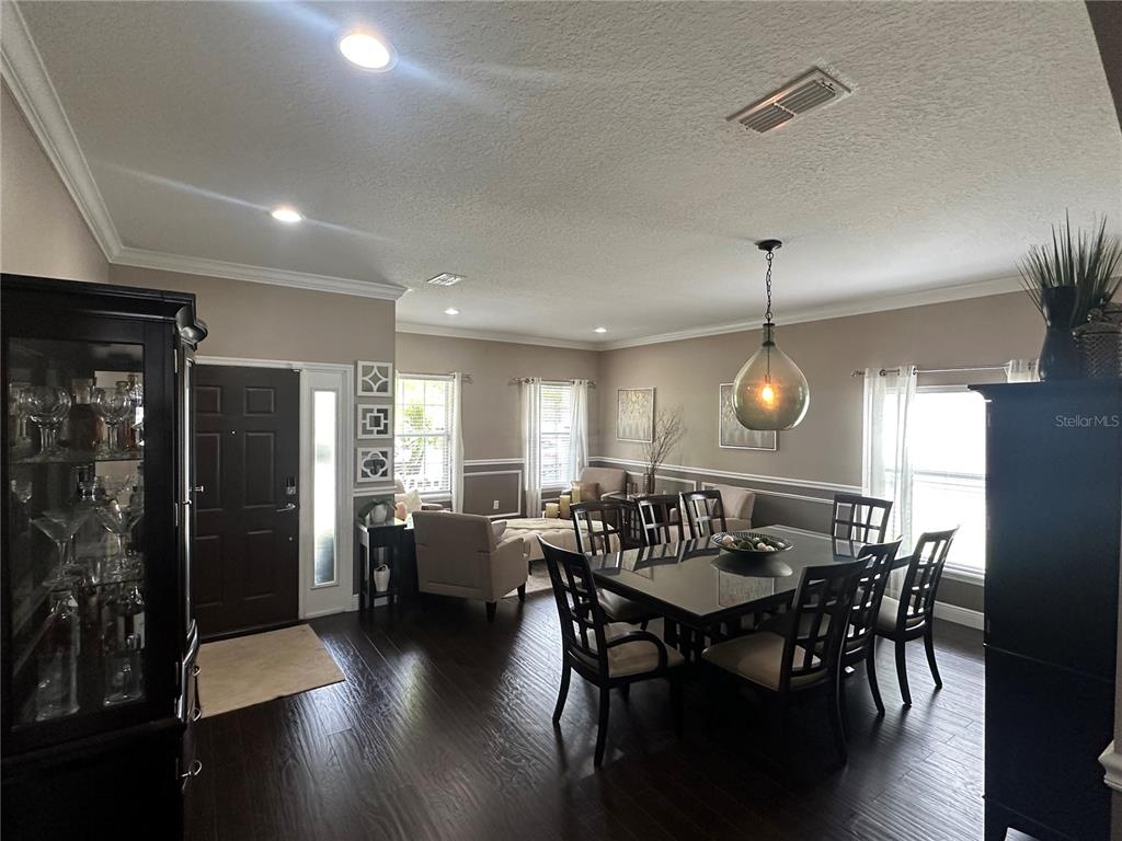 A dining room with dark wood floors, a glass-topped table, and an adjacent seating area — 2131 RIBBON FALLS PARKWAY, ORLANDO, FL