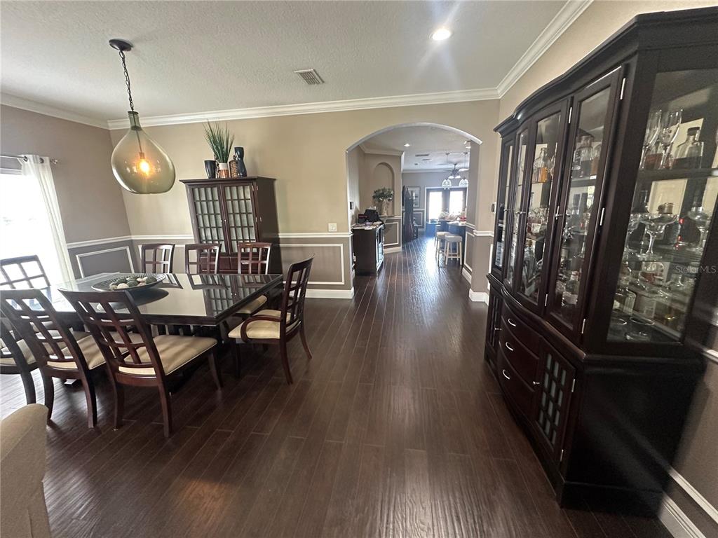 A dining room features dark wood furniture, hardwood floors, and an arched entryway to another room — 2131 RIBBON FALLS PARKWAY, ORLANDO, FL