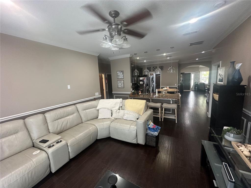 A living room with a sectional sofa flows into an open kitchen with a breakfast bar — 2131 RIBBON FALLS PARKWAY, ORLANDO, FL