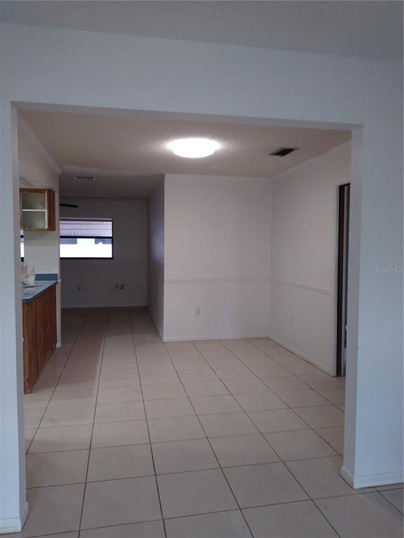 An interior view shows a tiled dining area leading to a kitchen with wooden cabinets — 1725 TUMBLEWEED DRIVE, HOLIDAY, FL