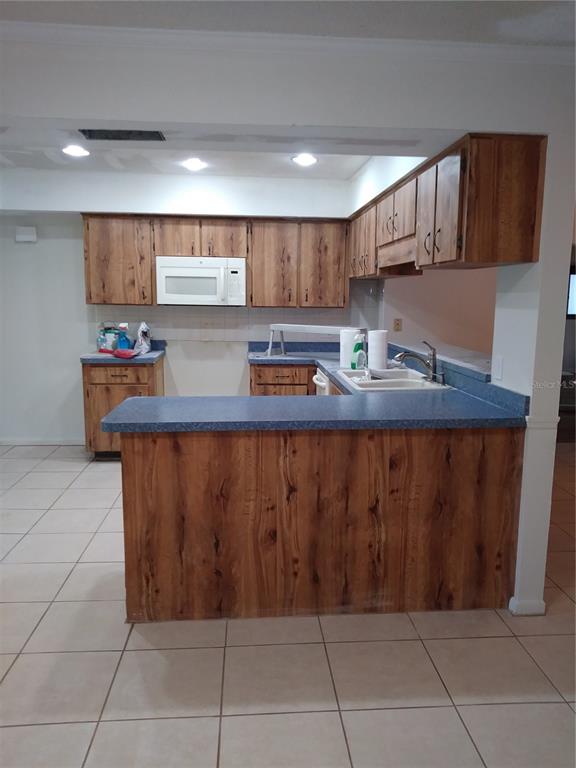 A kitchen features wood-grain cabinets, blue countertops, and tile flooring in an open layout — 1725 TUMBLEWEED DRIVE, HOLIDAY, FL