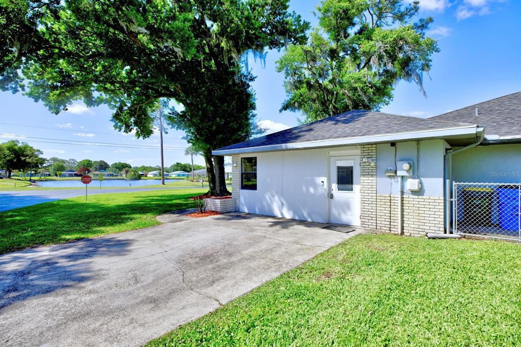 A concrete driveway leads to the side entrance of a house with a grassy yard — 3601 DIVOT ROAD, SEBRING, FL