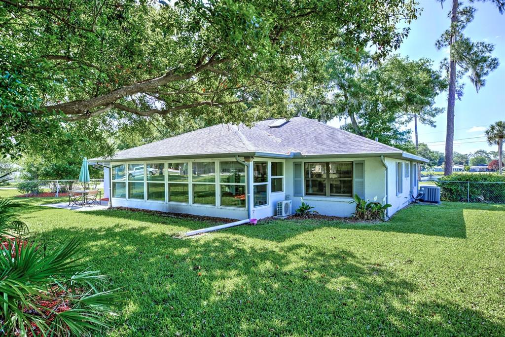 A single-story house with a large sunroom, white exterior, and a spacious green backyard — 3601 DIVOT ROAD, SEBRING, FL