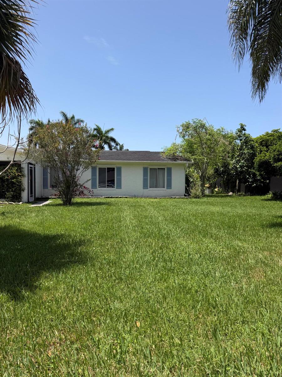 A white single-story house with blue shutters sits behind a large, grassy lawn — 3079 Indian Trail, Lake Worth FL 33462, LAKE WORTH, FL