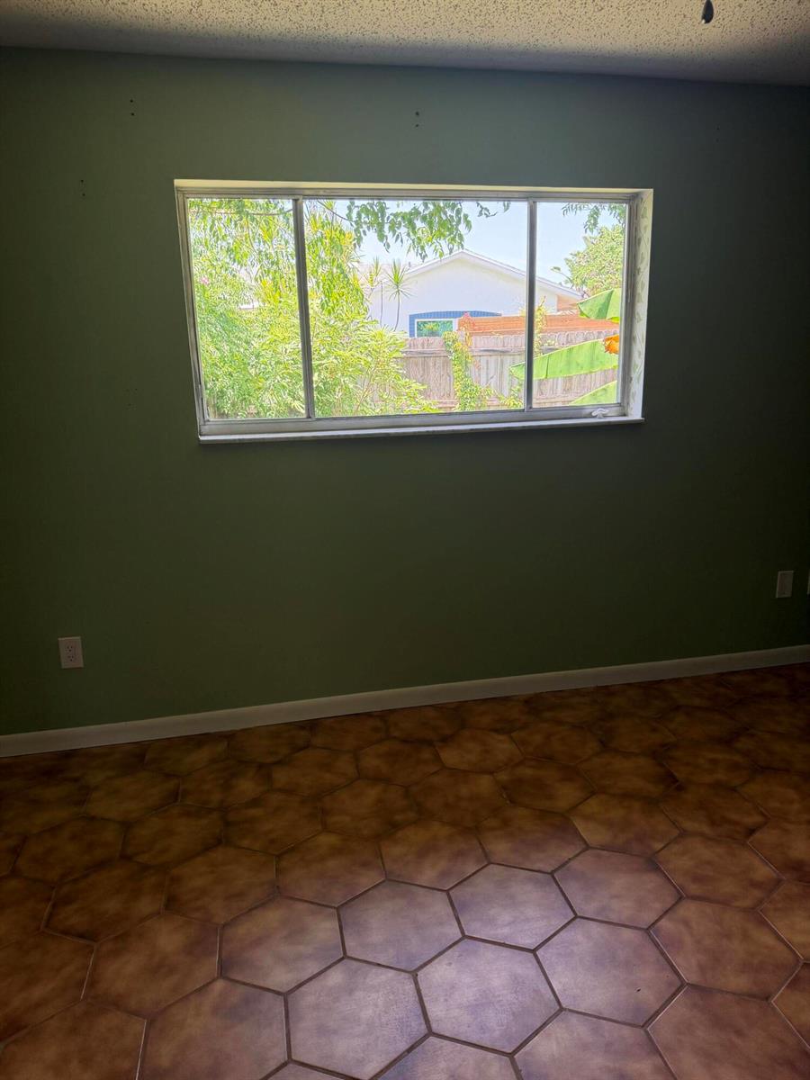 A room with green walls, brown hexagonal floor tiles, and a large horizontal sliding window — 3079 Indian Trail, Lake Worth FL 33462, LAKE WORTH, FL