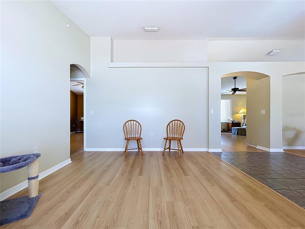 A spacious room with light wood flooring, two wooden chairs, and arched doorways — 12803 YARN PLACE, RIVERVIEW, FL