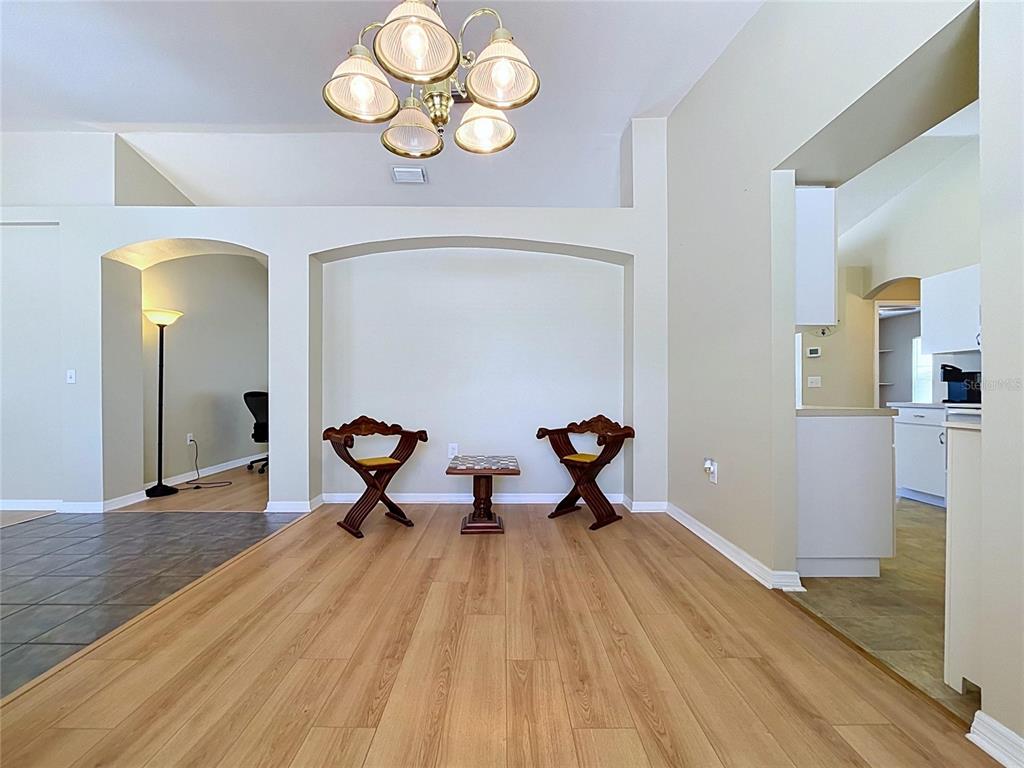 A dining area features light wood flooring, a central arched wall niche, and a chandelier — 12803 YARN PLACE, RIVERVIEW, FL