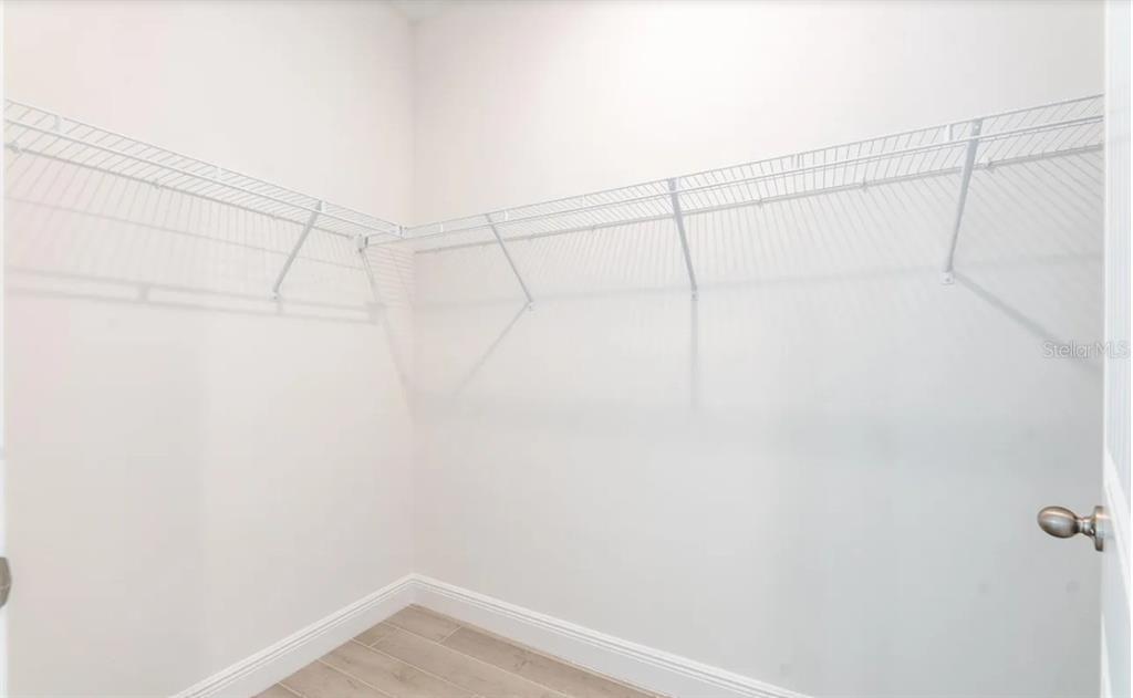 A walk-in closet features white walls, light wood-look tile flooring, and white wire shelving — 335 FRANZING ST SW, PALM BAY, FL
