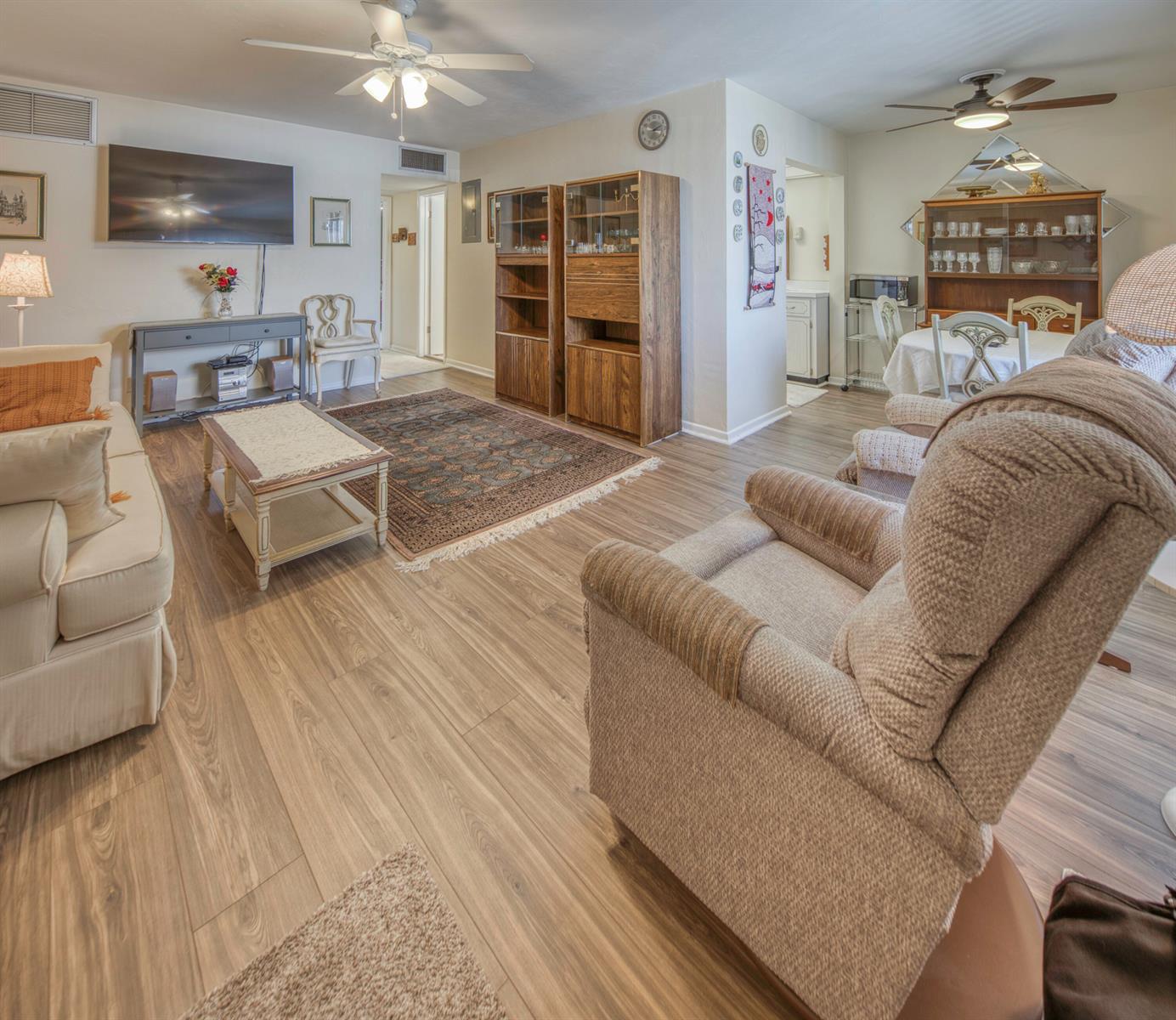 A living room with wood-look flooring, a beige sofa, a recliner, and a dining area — 1980 Sunset Avenue # 19, FL 33461, FL