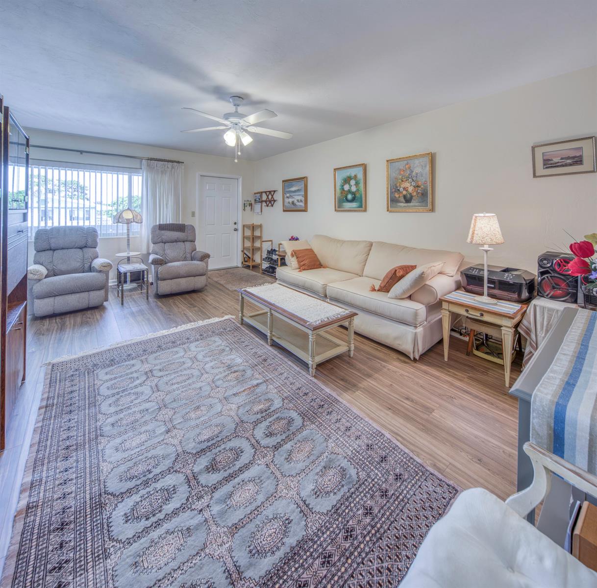 A living room features a beige sofa, two recliners, a patterned area rug, and wood-look flooring — 1980 Sunset Avenue # 19, FL 33461, FL