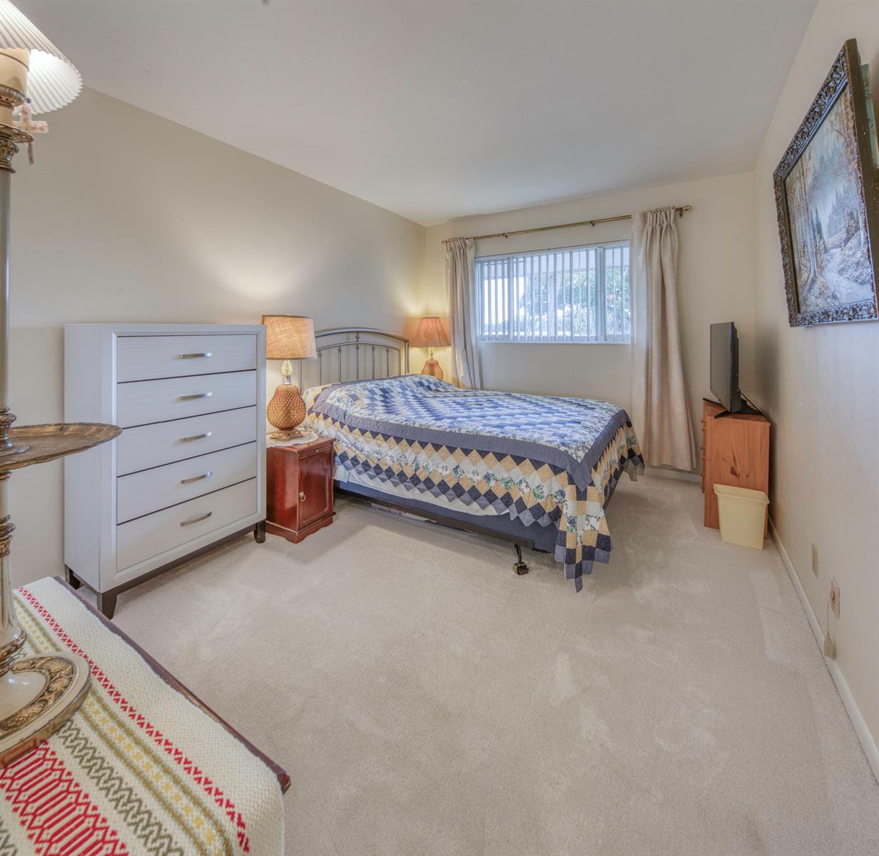 A bedroom features a bed with a patterned quilt, a white dresser, and beige carpeting — 1980 Sunset Avenue # 19, FL 33461, FL