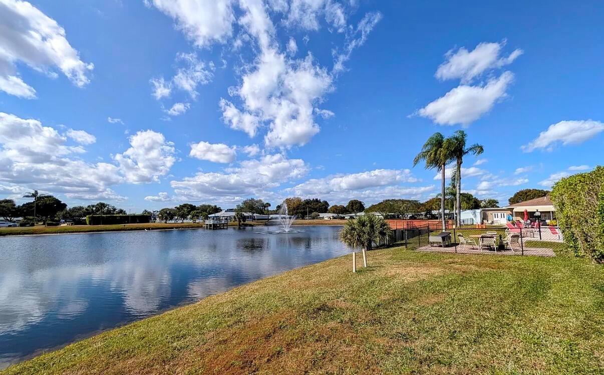 A grassy lawn slopes down to a pond with a fountain under a blue sky — 370 High Point Boulevard # C, Delray Beach FL 33445, DELRAY BEACH, FL