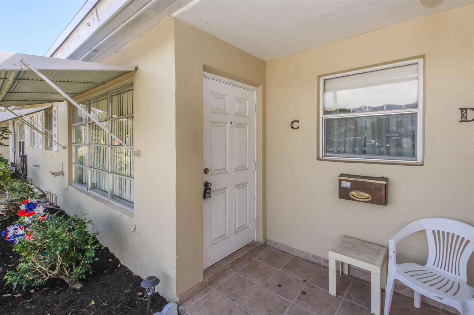 The exterior of a beige apartment unit features a white door labeled C and a mailbox — 370 High Point Boulevard # C, Delray Beach FL 33445, DELRAY BEACH, FL
