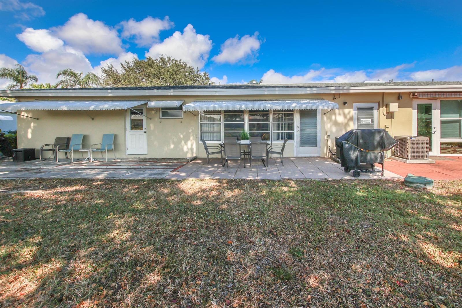 The exterior of a single-story house features a paved patio, outdoor furniture, and awnings — 370 High Point Boulevard # C, Delray Beach FL 33445, DELRAY BEACH, FL