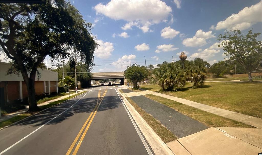 A paved road leads toward an overpass under a blue sky with scattered clouds — 713 S WESTMORELAND DRIVE, ORLANDO, FL