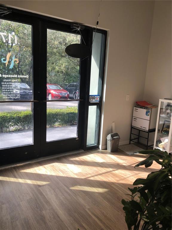 A commercial interior features a glass-paned double door, light wood flooring, and a small refrigerator — 3370 ROUSE ROAD UNIT 117, ORLANDO, FL